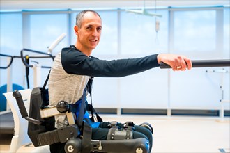 Mechanical exoskeleton. Portrait of disabled person with robotic skeleton in rehabilitation trying to get up alone