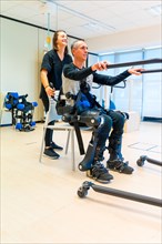 Mechanical exoskeleton. Female physiotherapy doctor assistant lifting disabled person with robotic skeleton to get up. Futuristic rehabilitation