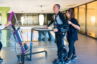 Mechanical exoskeleton. Female physiotherapy doctor helping disabled person with robotic skeleton to walk. Futuristic rehabilitation