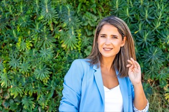Life balance of a mature casual businesswoman smiling at camera outdoors next to a greenery wall