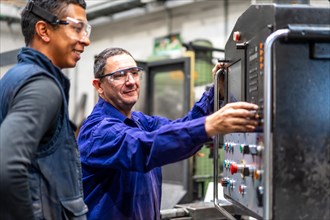 Instructor teaching the trade to a metal industrial factory worker in the numerical control sector