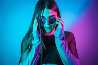 Futuristic studio portrait with neon lights of Non binary gender person wearing sunglasses