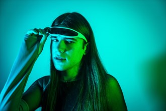 Futuristic studio portrait with neon lights of a cute transgender person putting on smart goggles