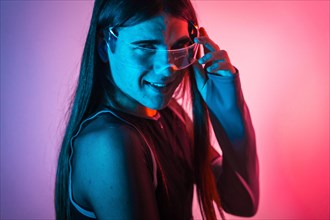 Futuristic studio portrait with neon lights of a cute non-binary person using smart goggles