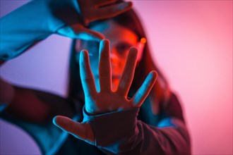 Futuristic studio portrait with neon lights of a Non binary person gesturing with hands while using Virtual reality goggles