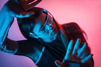 Futuristic studio portrait with neon lights of a transgender person moving hands while using smart goggles