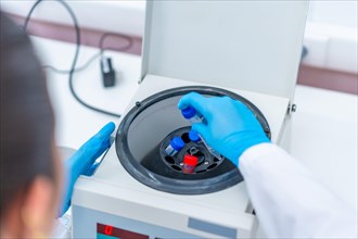 Top close-up view of a scientist introducing blood samples in a centrifuge machine