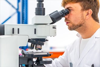 Close-up of a concentrated biologist using microscope during research in laboratory