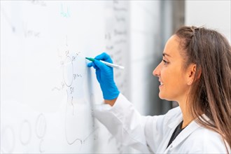 Side view of a young female biologist using a white board to write data in a lab