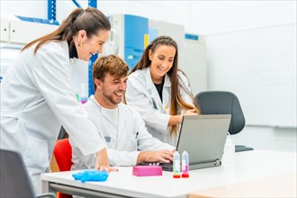 Smiling group of doctors using laptop in a cancer research laboratory