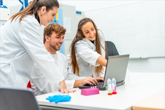 Scientist pointing the screen of a laptop next to colleagues in a research laboratory