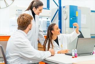 Scientists looking at samples while working with laptop sitting on a table in a lab