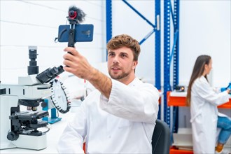 Young and Handsome scientist recording a video using phone inside a research laboratory