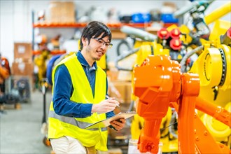 Young japanese engineer in charge of controlling an industrial production line of robotic arms