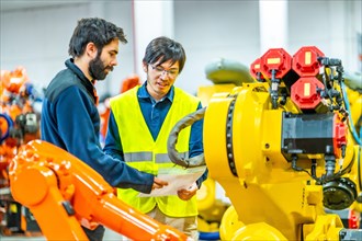 International team of engineers reading an inform in a industry of robotic arms
