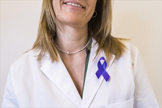 Close-up of purple ribbon pinned on white lab coat of female doctor