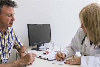 Female doctor writing prescription to her patient