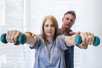 Male physiotherapist teaching a patient how to use dumbells for wellness and disability support