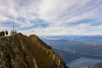 Aerial View over a Beautiful Meteorological and Communication Station on Mountain Peak and Snow Capped Monte Rosa and Lake Lugano in a Sunny Day in Monte Generoso