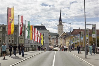Flags on the Drau bridge with parish church