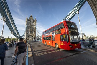 Red double-decker bus drives over Tower Bridge in London