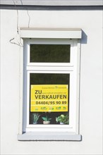Window on an old house with sign for sale