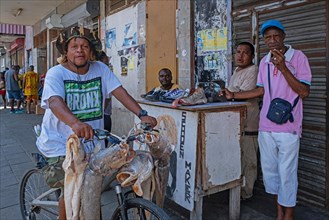 Selling large fish from a bicycle and a small shoe repair stand in the centre of Paramaribo