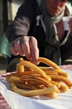Close-up of hand picking a churro from a plate of churros