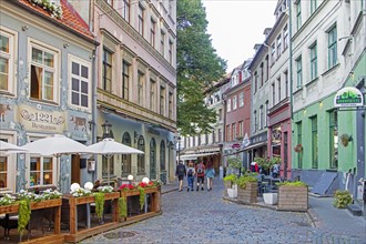 Cobbled street with restaurants and cafes in the historic city centre of Riga