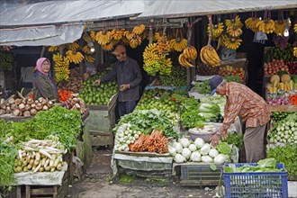 Indonesian vendor selling fruit and vegetables on display in front of grocery shop