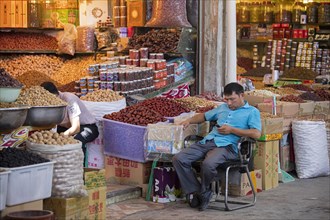 Uyghur vendor selling nuts and dried fruit in food shop in the city Kashgar