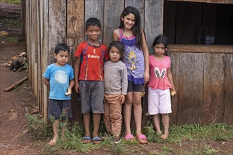 Paraguayan children posing in front of primitive wooden house in the town Edelira in rural Itapua
