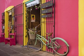 Colourful pink and yellow storefront with decorative bicycle in the city Puebla