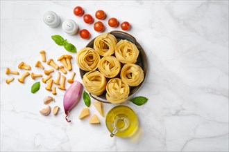 Raw ingredients for mushroom pasta scattered on marble background