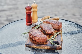 Tree juicy grilled strip steaks served on wooden cutting board