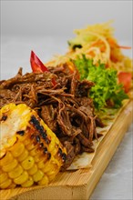 Pulled beef served with grilled corn and pickled cabbage