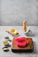 Raw ahi tuna steak on cutting board with spice