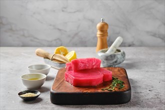 Raw ahi tuna steak on cutting board with spice and herbs