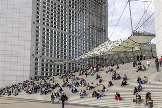 People sitting on the steps of the Grande Arche de la Defense skyscraper
