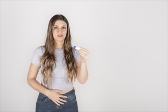 Portrait of a young blond woman holding pregnancy test feeling shocked