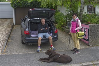 Couple with dog in front of departure by car