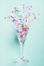Glass with confetti turquoise background