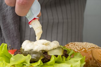 Hand putting mayonnaise burger