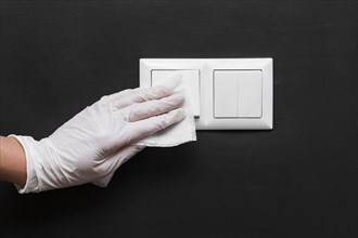 Hand with glove disinfecting light switches