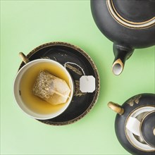 Herbal tea bag cup with teapot sugar cubes green background