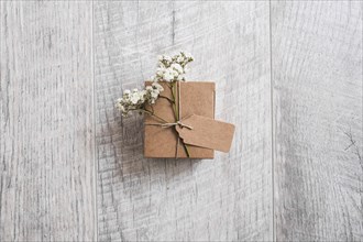 Overhead view cardboard box tied with tag baby s breath flowers wooden desk