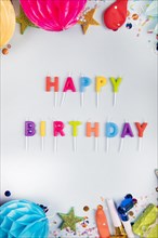 Overhead view colorful happy birthday candles with party items white backdrop