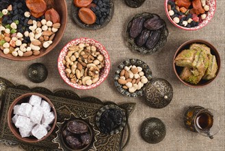 Overhead view turkish tea dates lukum dried fruits nuts jute tablecloth