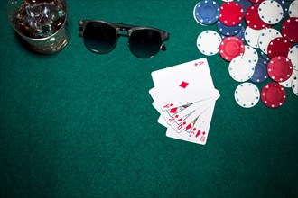Playing card casino chips whisky glasses sunglasses green poker background