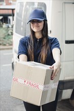 Portrait smiling female courier with cardboard box